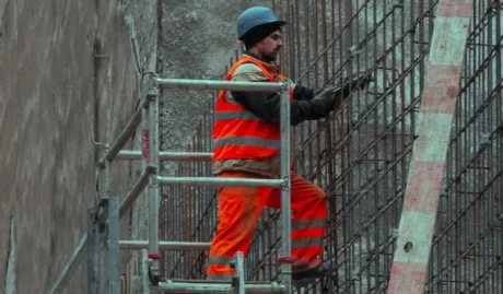 A workman in high vis jackaet and trousers on an elevated scaffolding platform used on a blog about insurance for tradies