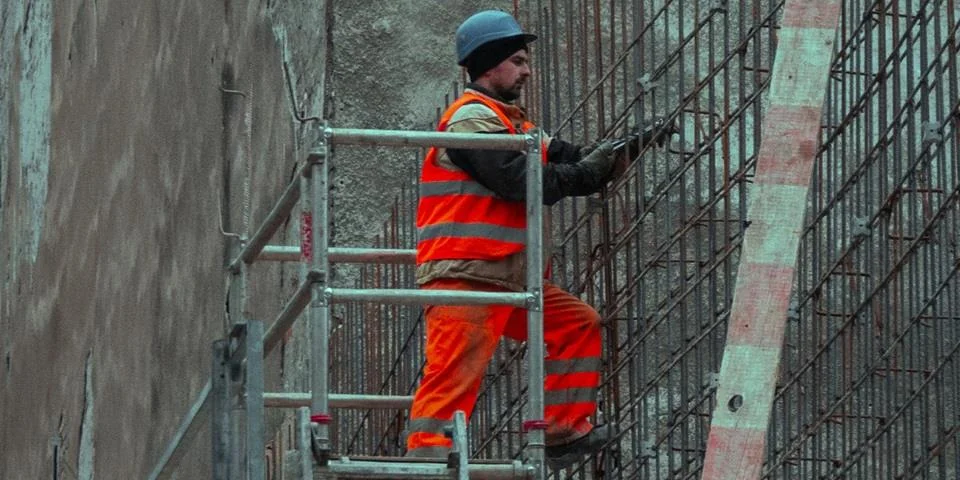 A workman in high vis jackaet and trousers on an elevated scaffolding platform used on a blog about insurance for tradies