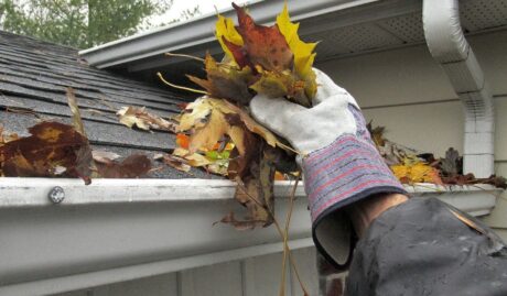 clearing gutters of leaves to prepare a property for winter