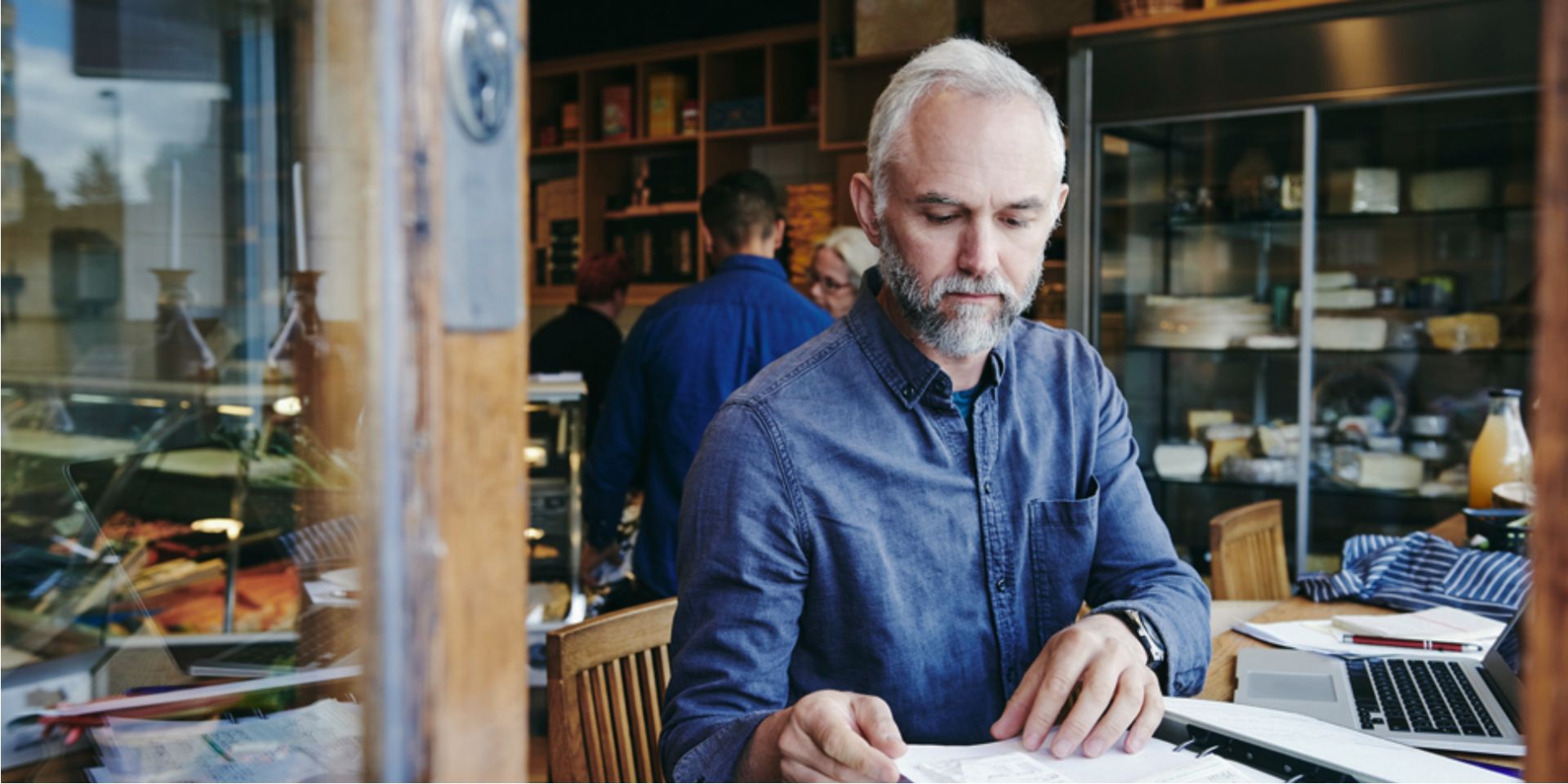 man sitting reviewing papers with an open laptop used on a blog about business insurance requirements and EOFY